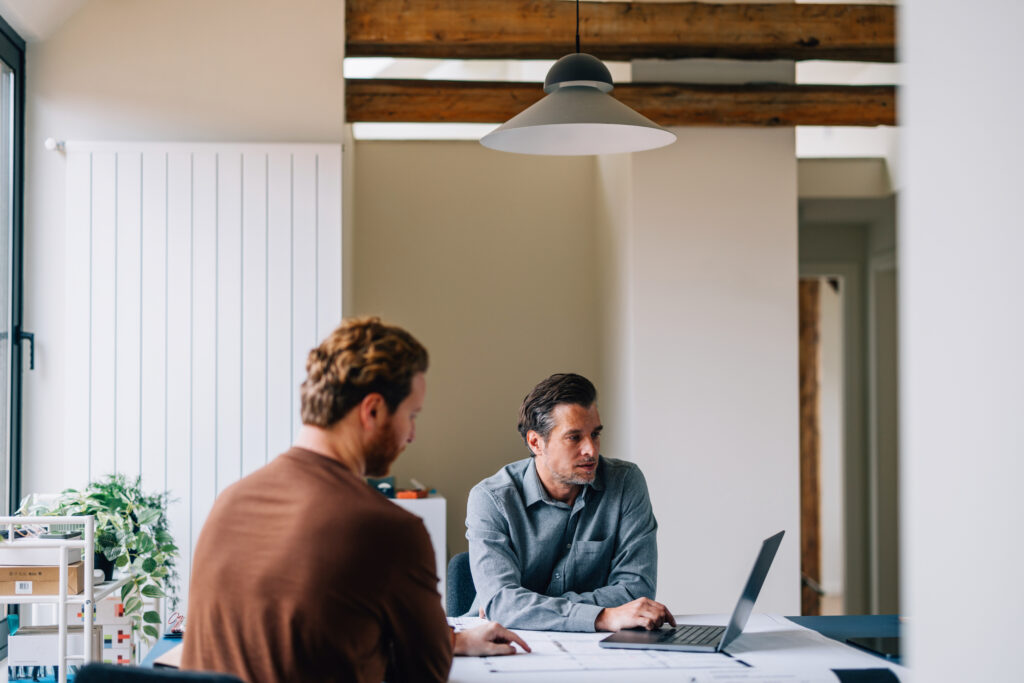 Two male colleagues collaborating on a project in a well-lit, spacious office setting.